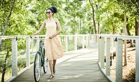 Woman walking bicycle along boardwalk trail