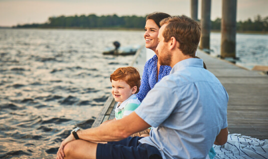 Family sitting on boardwalk along Cape Fear River in Riverlights