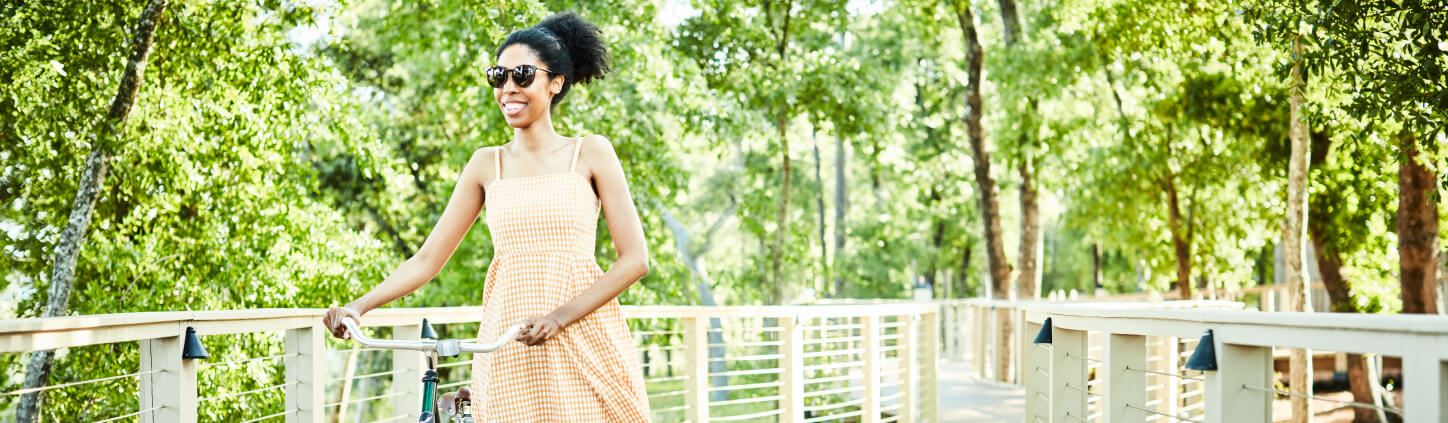 Woman walking bicycle along boardwalk trail in Riverlights